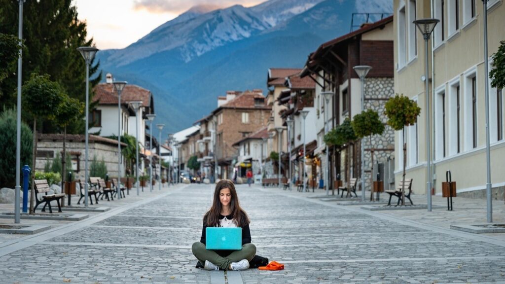 a woman sitting on the street with a laptop